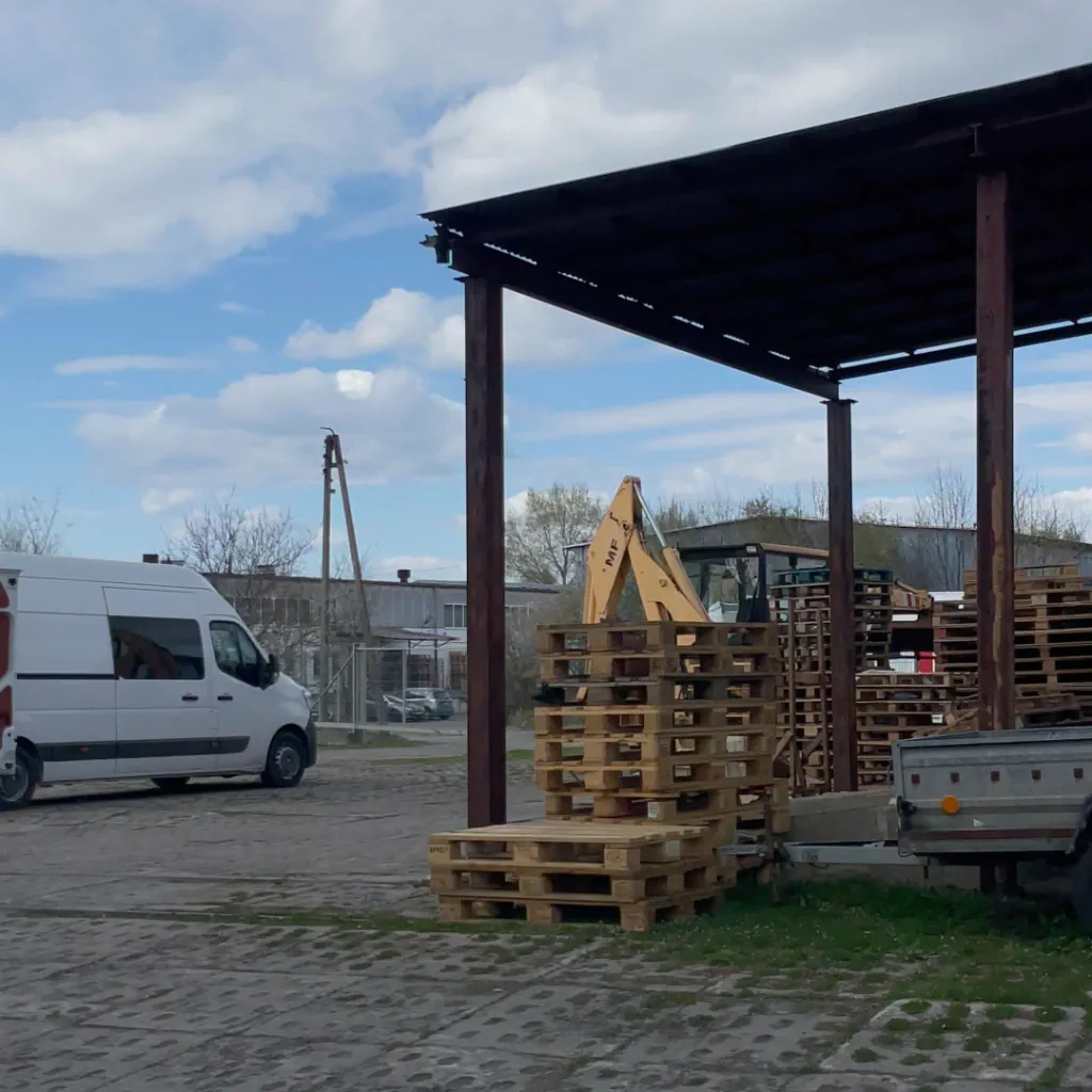 Территория склада Poromnyk в Польше — микроавтобус и палеты под навесом